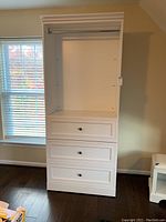 Full front view of the white wardrobe cabinet showing three drawers and hanging compartment
