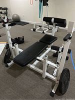 Front-left perspective showing bench, leg developer and barbell rack