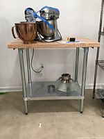 Front view of wood block kitchen table with metal legs and lower metal shelf with items on top