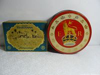 Two vintage tins side by side, rectangular Teekanne Pompadour blue and gold tin, and round red and gold tin with lion emblem.