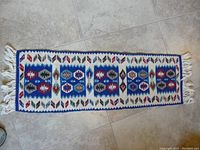 Full view of vintage blue and white woven rug with geometric patterns and fringed ends