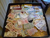 Overview of assorted foreign banknotes spread on black tray