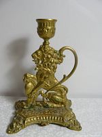 Front side view of heavy brass lion candle holder with detailed lion figure and ornate base.