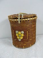 Front view of cylindrical birch bark basket showing decorative yellow and green flower motif