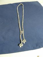 Full view of the necklace on a blue cloth background showing the full length with a drop centerpiece of stones.