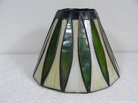 Side view of cone-shaped leaded glass lamp shade with alternating green and cream glass panels, showing slight iridescence and black lead cames separating each panel.