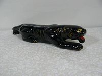 Side view of black panther figurine showing full body and glossy ceramic finish.