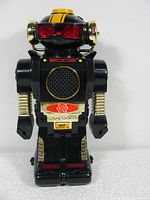 Front view of the black and gold Robot 2002 toy showing red plastic eyes, speaker grill, and detailing.