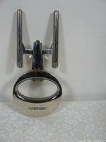 Front view of metal bottle opener shaped like USS Enterprise starship from Star Trek.