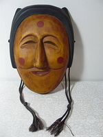 Full front of mask showing smiling face with closed eyes, red round marks on cheeks and forehead, black painted edges