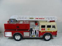 Side view of Tonka Fire Rescue firetruck showing detailed control panel and ladder on top.