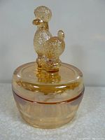 Front view of vintage amber glass vanity jar with textured poodle figurine on lid.