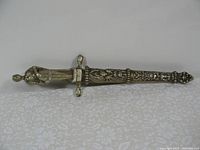 Envelope opener shaped like a Roman sword with ornate patterns on the sheath and handle.