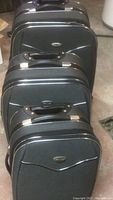 Frontal view showing three sizes of black soft luggage stacked vertically with visible handles and zippers