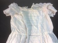 Close-up of bodice showing lace trim around neckline and pintuck pleats.