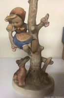 Photo of Hummel figurine showing girl climbing tree with dog at base.