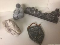 Four Indigenous pieces including soapstone swan, animal head carving, heart-shaped plaque with label, and rectangular polar bear plaque.