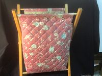 Front view of the quilted fabric knitting bag mounted on a wooden stand, showing floral pattern and wooden frame structure.