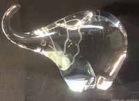 Side view of clear glass elephant art figurine with raised trunk, shown on black background.