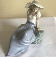 Front and side view of the Lladro porcelain figurine showing woman in hat with birds.