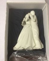 Porcelain dancing couple figurine in original box with protective packaging, shown on wood stand.