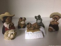 Front view of the seven Peruvian clay nativity figures including humans and animals arranged in a line.