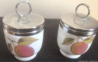 Two Royal Worcester egg coddles, white porcelain with peach fruit design and metal lids with rings