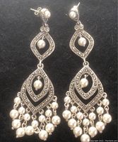 Photo of a pair of sterling silver chandelier earrings with pearl beads and marcasite detailing on a black background.