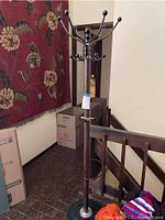 Full view of the coat rack placed near stairs, showing its height and shape