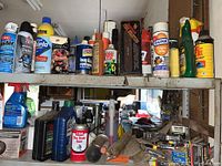 Shelf with assorted car cleaners, dust remover sprays, motor oils in bottles and cans, spray bottles, and boxes of staple gun staples.