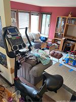 Schwinn stationary exercise bike positioned in living area, showing the padded seat, part of the handlebars, and the base setup.