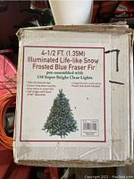 Original box showing the label with product details including height, illuminated lights, and tree type.