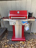 Front view of the red KitchenAid two-burner grill with closed lid, control panel, and side shelves