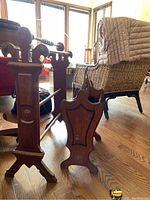Quilt stand showing turned rods and carved end panel with circular detail.
