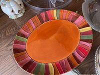 Oval ceramic platter with orange center and multicolored striped border