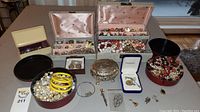 Full view showing multiple jewelry boxes, tins, and loose costume jewelry pieces including yellow bangles and pearl-like beads.