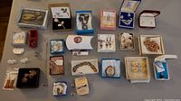 Overview photo showing all pieces of costume jewelry including boxed brooch sets, pins, earrings and bracelets arranged on a flat surface.