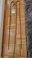 Full view of three English crook handle school canes laid on parquet floor showing their lengths and handles.