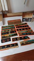 Multiple vintage glass slides arranged on table with colorful painted scenes and a metal slide viewer in box