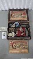 Overview of the open box showing the metal parts, wheels, pulleys, strings, and instruction manual laid out inside.