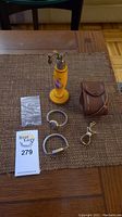 Full view of all items on table including perfume bottle, watches, leather case, and clip.