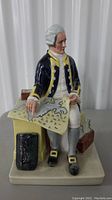 Front view showing full figurine of seated Captain Cook holding map