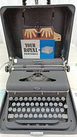 Typewriter inside its case with included paperwork and brochure visible