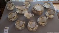 Full view of the tea set including teacups, saucers, creamer, gravy boat on table