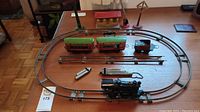 Overview of assembled oval track with locomotive, tender, passenger cars, building, signals, and whistle