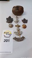 Overview photo showing all pins, badges, buttons and brass collar badge grouped with auction lot card