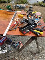 Wide angle view on table showing assorted clamps, hand plane, rulers, flashlights, and various hand tools
