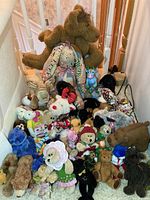Full view of the collection of various stuffed bears and plush animals arranged on stairs and floor area