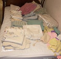 Full view of quilt, sheets, pillowcases and doll clothes arranged on queen bed
