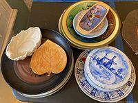 Overview of various decorative plates and serving dishes including leaf-shaped dishes and blue and white plate.